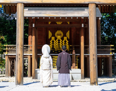 伝統的な神前式で、新郎新婦が神社の拝殿に並び立ち誓いを捧げる厳かな瞬間を切り取った一枚。