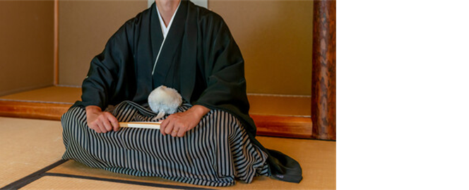 黒紋付羽織袴は、男性の和装における最も格式の高い正礼装です。
黒無地の羽織と着物に、家紋を5つ入れ仙台平(せんだいひら)と呼ばれる縞模様の袴を合わせます。
挙式から披露宴まで幅広く着用でき、花嫁の白無垢や色打掛と並び、伝統的な和婚スタイルを完成させます。