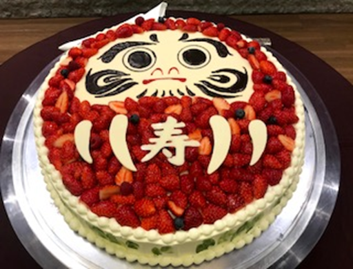 「寿」の文字が輝く、縁起の良いだるまケーキ!いちごがたっぷり使われ、お祝いの席を華やかに彩ります。