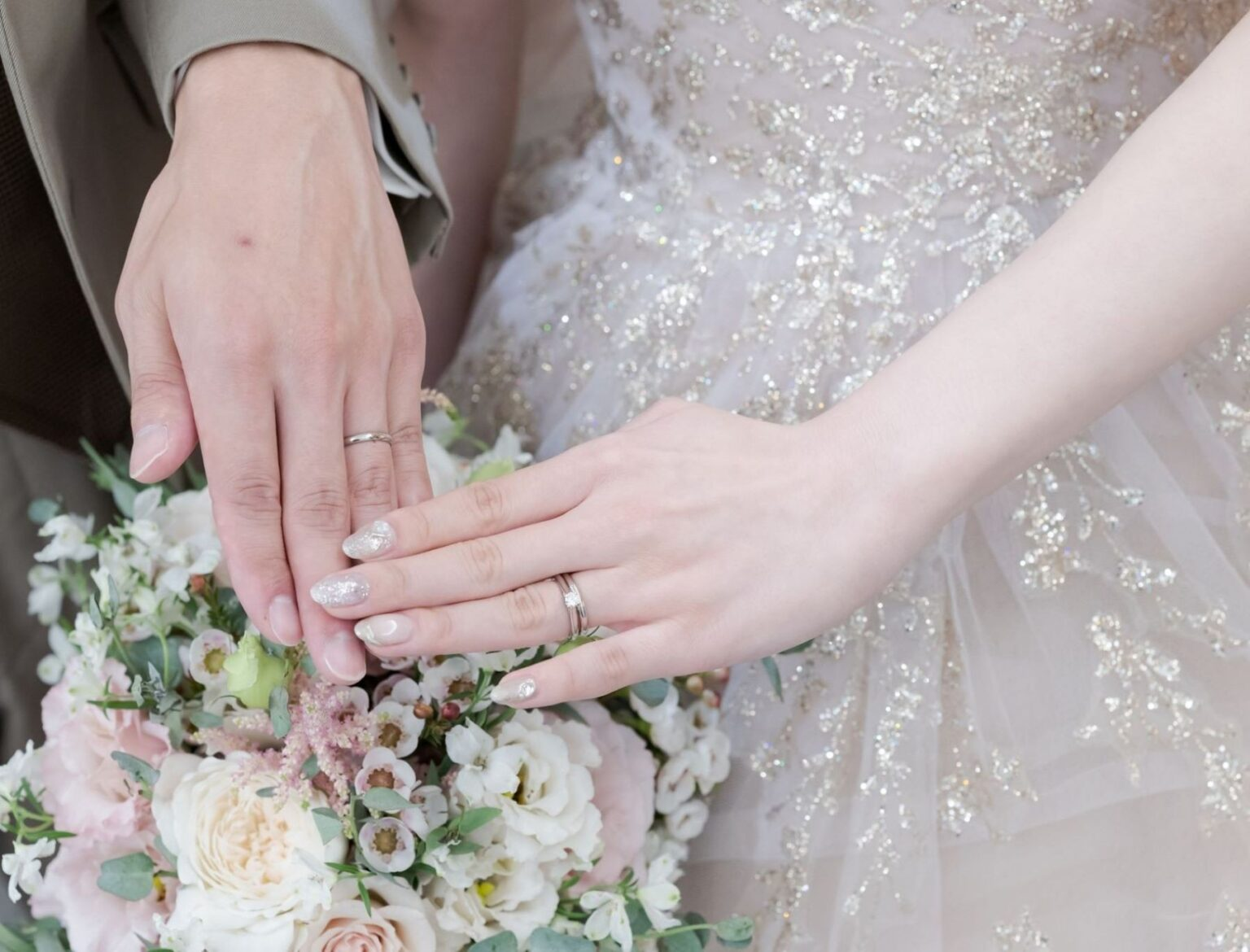 華やかなブーケを背景に、新郎新婦が結婚指輪をそっと重ねた手元ショット。ビアンカーラヒルサイドテラスでも人気のカットで、指輪交換後の幸せな瞬間を美しく残せる写真