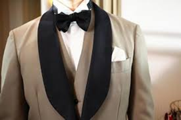 【名古屋市結婚式場ビアンカーラテラス】洗練されたベージュのジャケットに黒のショールカラーと蝶ネクタイを合わせた、シックでオシャレな新郎様のタキシード。名古屋市にある市の邸宅で叶える、大人なウェディングに相応しい洗練されたメンズスタイルを詳細に描写した一枚です。