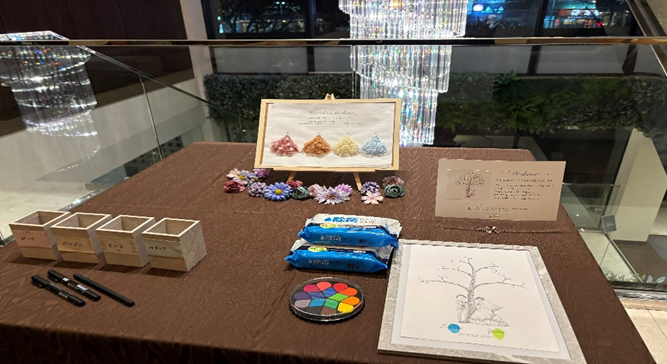 ブラウンのクロスが掛けられたテーブルに、ウェディングツリー用紙、カラーパレット、造花、案内カード、ペン立てなどが並ぶ、ビアンカーラヒルサイドのウェルカムスペース。