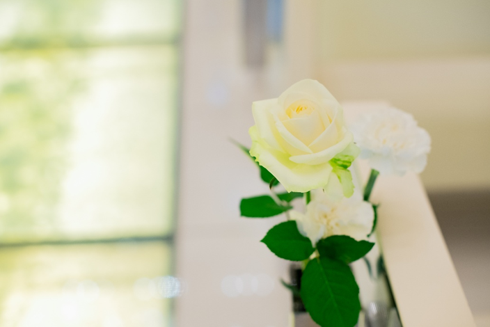 名古屋市結婚式場ビアンカーラヒルサイドテラス結婚式の清楚な雰囲気を引き立てる、みずみずしい白いバラの装花。光が差し込む明るいチャペル内でのクローズアップ。