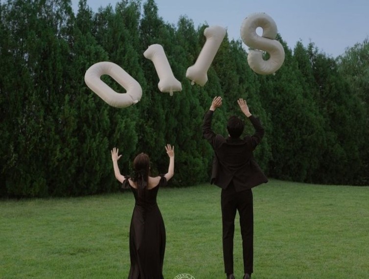 名古屋市の結婚式場ビアンカーラヒルサイドテラスの緑豊かなガーデンで、挙式日の数字バルーンを空に投げてお祝いする新郎新婦の後ろ姿のフォト。